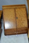 AN EDWARDIAN OAK STATIONERY BOX, hinged top above sloped double doors opening to reveal a fitted