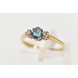 A 9CT GOLD THREE STONE GEM RING, the central oval blue topaz flanked by brilliant cut diamonds,
