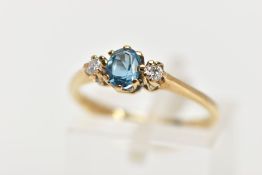 A 9CT GOLD THREE STONE GEM RING, the central oval blue topaz flanked by brilliant cut diamonds,