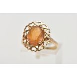 A YELLOW METAL CITRINE RING, designed with a claw set oval cut citrine, within an openwork heart