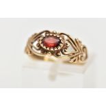 A 9CT GEM RING, the central oval red gem, assessed as paste, to the scrolling openwork design to the