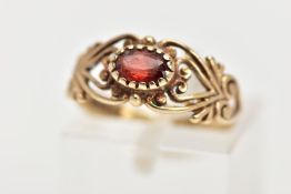 A 9CT GEM RING, the central oval red gem, assessed as paste, to the scrolling openwork design to the