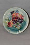 A MOORCROFT POTTERY SPRING FLOWERS PATTERN PLATE, on a blue/green ground, painted WM initials and