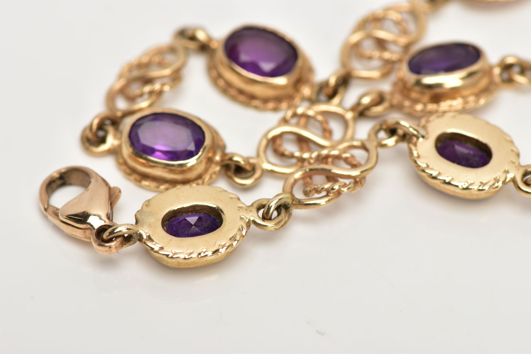 A 9CT GOLD AMETHYST LINE BRACELET, designed with seven oval cut amethysts, each with a collet - Image 3 of 4