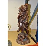 A 20TH CENTURY CHINESE CARVED HARDWOOD FIGURE OF A JOVIAL MAN, holding a staff in both hands, a