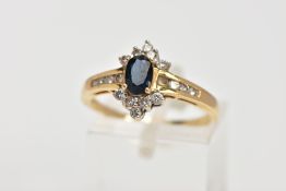 AN 18CT GOLD SAPPHIRE AND DIAMOND CLUSTER RING, centring on an oval cut blue sapphire, within a