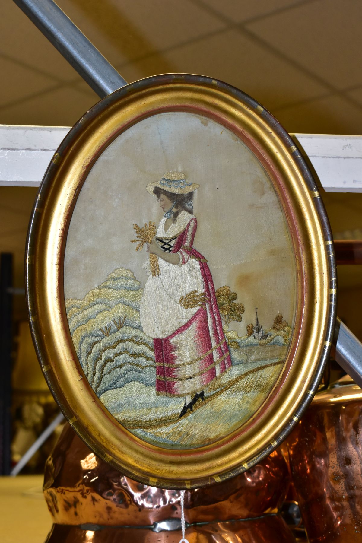 A LATE 18TH CENTURY EMBROIDERED SILKWORK PICTURE OF A LADY HARVESTING CORN, church to the
