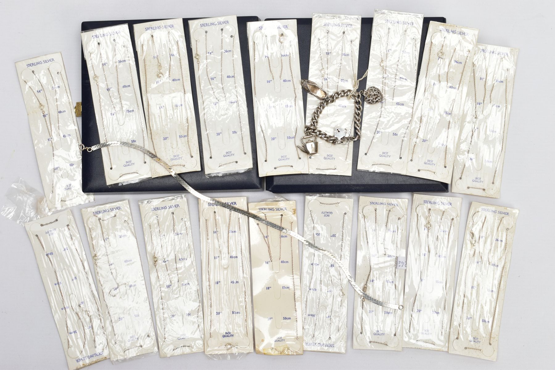 A SELECTION OF PACKAGED CHAINS, FLAT HERINGBONE CHAIN AND A CHARM BRACELET, the bracelet with four