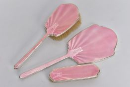 A 1930'S SILVER VANITY SET, comprising of a mirror, and two brushes, one with a handle, with pink