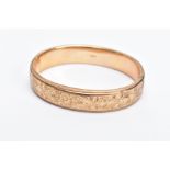 A 9CT GOLD OVAL HALF ENGRAVED OVAL HINGED BANGLE, half engraved with a floral and foliate fancy