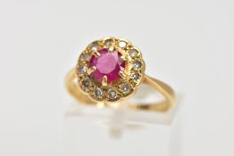 A YELLOW METAL RUBY AND DIAMOND CLUSTER RING, designed with a central claw set circular cut ruby,