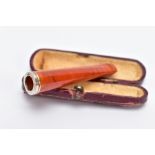 A CASED FAUX AMBER CHEROOT HOLDER with white metal collar in a maroon case, 6cm