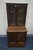 AN EARLY 20TH CENTURY OAK FOUR DOOR CUPBOARD, the top section glazed panel etched with the fleur