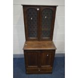 AN EARLY 20TH CENTURY OAK FOUR DOOR CUPBOARD, the top section glazed panel etched with the fleur