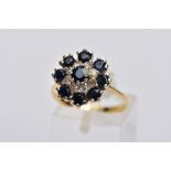 AN 18CT SAPPHIRE AND DIAMOND CLUSTER RING, the central circular sapphire within a tiered single