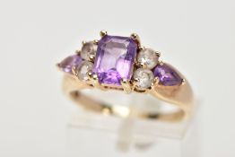 A 9CT GOLD GEM RING, designed as a central rectangular amethyst flanked by two circular colourless