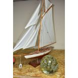 A MODEL YACHT ON STAND, length 83cm x height 81cm, together with a large glass dumpy weight, with