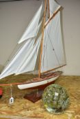 A MODEL YACHT ON STAND, length 83cm x height 81cm, together with a large glass dumpy weight, with