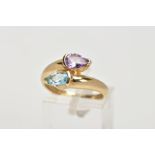 A 9CT GOLD AMETHYST AND TOPAZ CROSS OVER RING, designed as pear shape blue topaz and amethyst