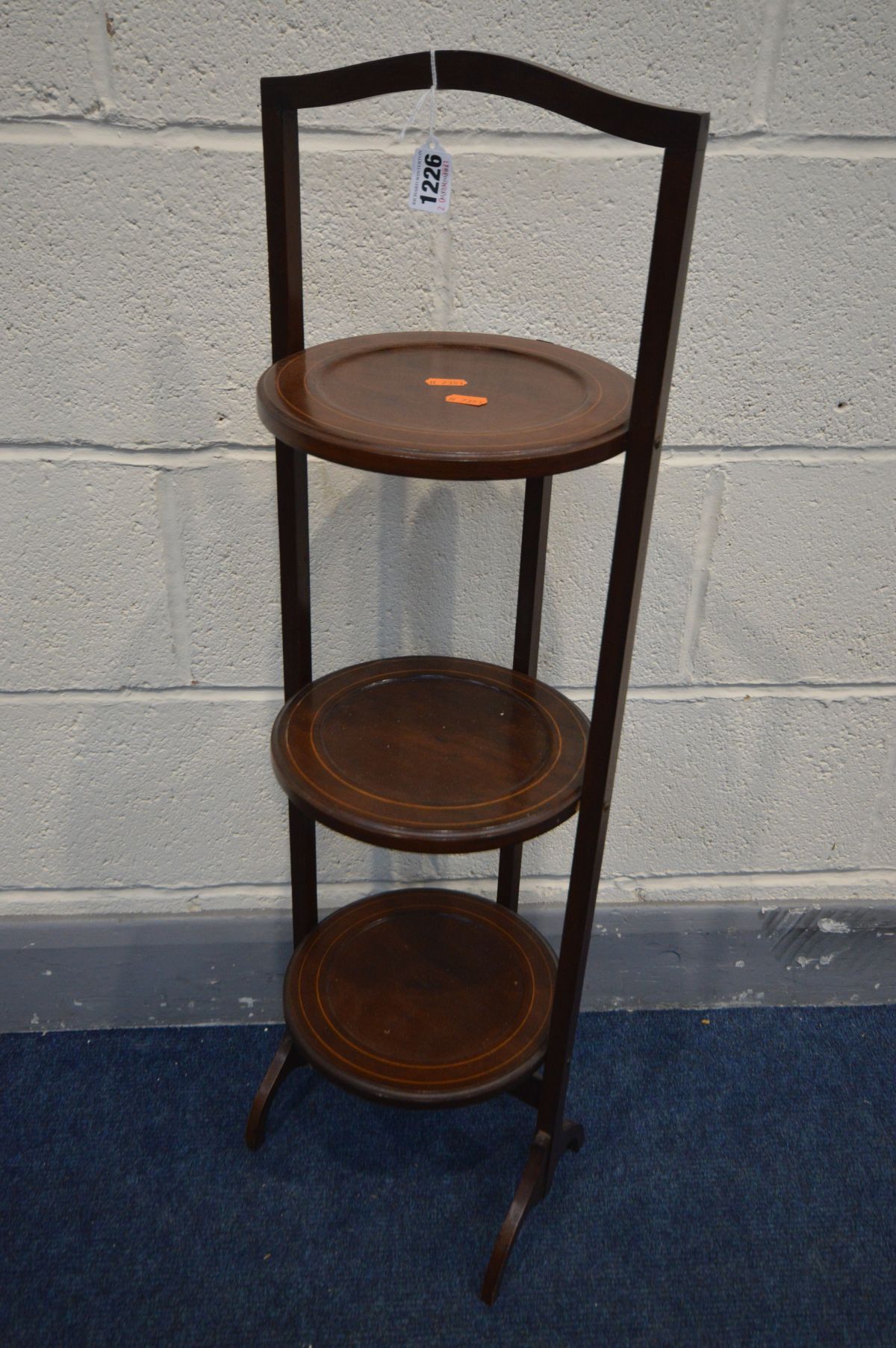 AN EDWARDIAN MAHOGANY AND INLAID THREE TIER FOLDING CAKE STAND