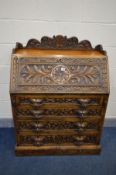 AN EARLY 20TH CENTURY OAK BUREAU, carved with scrolls, foliage and masks, gallery top, fall front