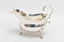 A GEORGE III SILVER GRAVY BOAT, with scalloped edge, scrolling handle and raised on step pad feet,