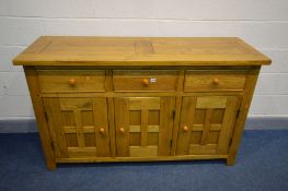 A SOLID OAK SIDEBOARD, with three drawers above triple panelled cupboard doors, width 157cm x
