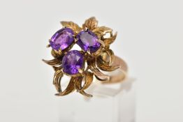 AN ORNATE FANCY AMETHYST DRESS RING, three oval cut amethysts claw set to a fancy foliate mount,