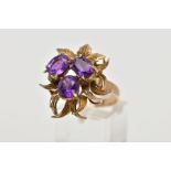 AN ORNATE FANCY AMETHYST DRESS RING, three oval cut amethysts claw set to a fancy foliate mount,