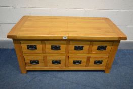 A SOLID OAK COFFEE TABLE with double sliding top compartment, and various drawers, length 111cm x