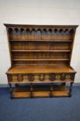 A 20TH CENTURY CARVED OAK DRESSER, 17th century style, the top with a hanging cornice, arched apron,