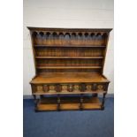 A 20TH CENTURY CARVED OAK DRESSER, 17th century style, the top with a hanging cornice, arched apron,