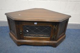 A DARK OAK JAYCEE CORNER TV CABINET, with a lead glazed door enclosing two shelves, width 103cm x