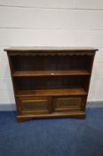 A REPRODUCTION OAK BOOKCASE, two open shelves above a double sliding door lunette section, on