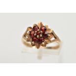 A 9CT GOLD GARNET DRESS RING, of a flower shape, set with seven circular cut garnets, textured