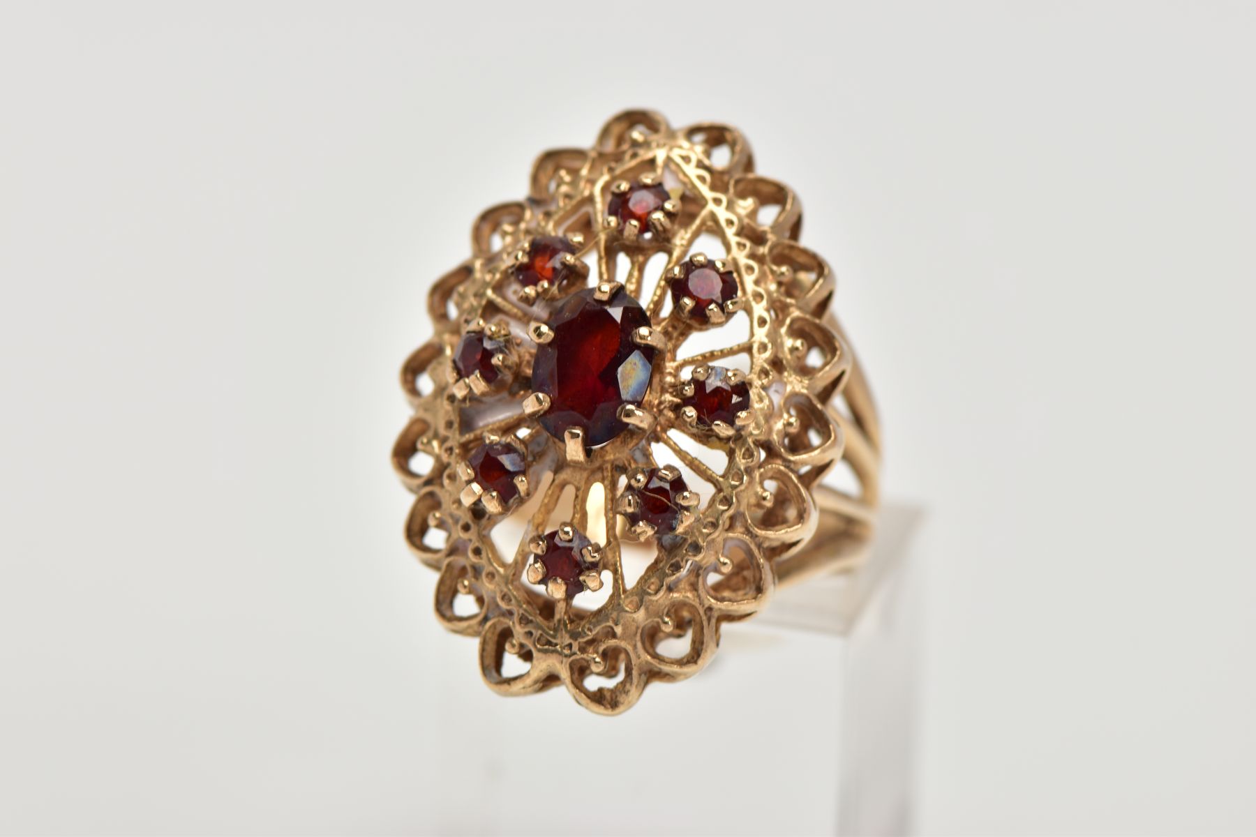A 9CT GOLD GARNET DRESS RING, of a large openwork marquise shape, set with circular cut garnets,
