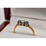 A YELLOW METAL THREE STONE RING, designed with a central, claw set old cut diamond, flanked with