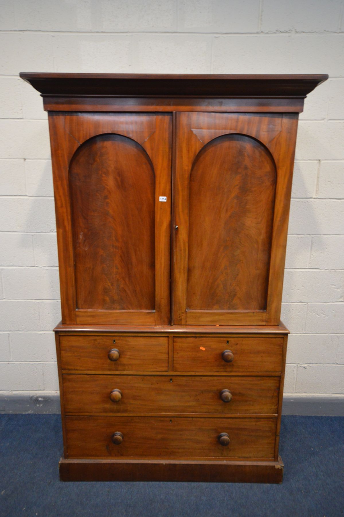 A VICTORIAN FLAME MAHOGANY LINEN PRESS, overhanging cornice, the double panelled doors enclosing