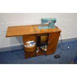 A VINTAGE SINGER SEWING MACHINE in an oak cabinet with sewing accessories (no PAT due to uninsulated