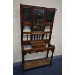 AN EARLY 20TH CENTURY OAK HALL STAND, with later tin panels flanking a bevelled edge mirror above