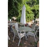 A METAL FRAMED GARDEN TABLE with glass top 91cm in diameter with four matching chairs and a