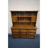 `A REPRODUCTION OAK DRESSER, the top with a central shelf flanked by two single cupboard doors,