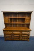 `A REPRODUCTION OAK DRESSER, the top with a central shelf flanked by two single cupboard doors,