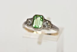 A YELLOW AND WHITE METAL DRESS RING, centring on an emerald cut green paste, flanked with circular