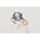 A YELLOW METAL DRESS RING, designed with a claw set circular cut pale blue stone assessed as