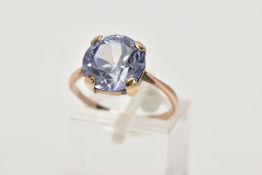 A YELLOW METAL DRESS RING, designed with a claw set circular cut pale blue stone assessed as