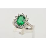 A 9CT WHITE GOLD CLUSTER RING, centring on an oval cut green stone assessed as paste, within a