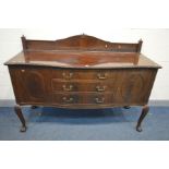 AN EDWARDIAN MAHOGANY SERPENTINE SIDEBOARD with a raised back with blind fretwork detail, on a
