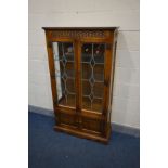 AN OAK OLD CHARM LEAD GLAZED DOUBLE DOOR CHINA CABINET, with three glass fixed shelves, above a