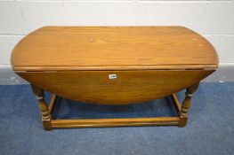 A LOW OAK OVAL TOP DROP LEAF COFFEE TABLE, length 107cm x open depth 96cm x closed length 53cm x